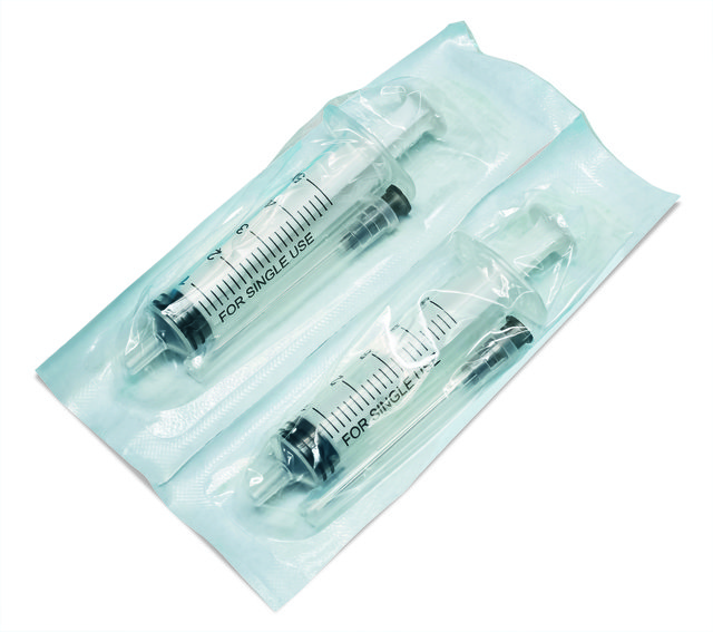 Disposable syringes in packaging on blue background